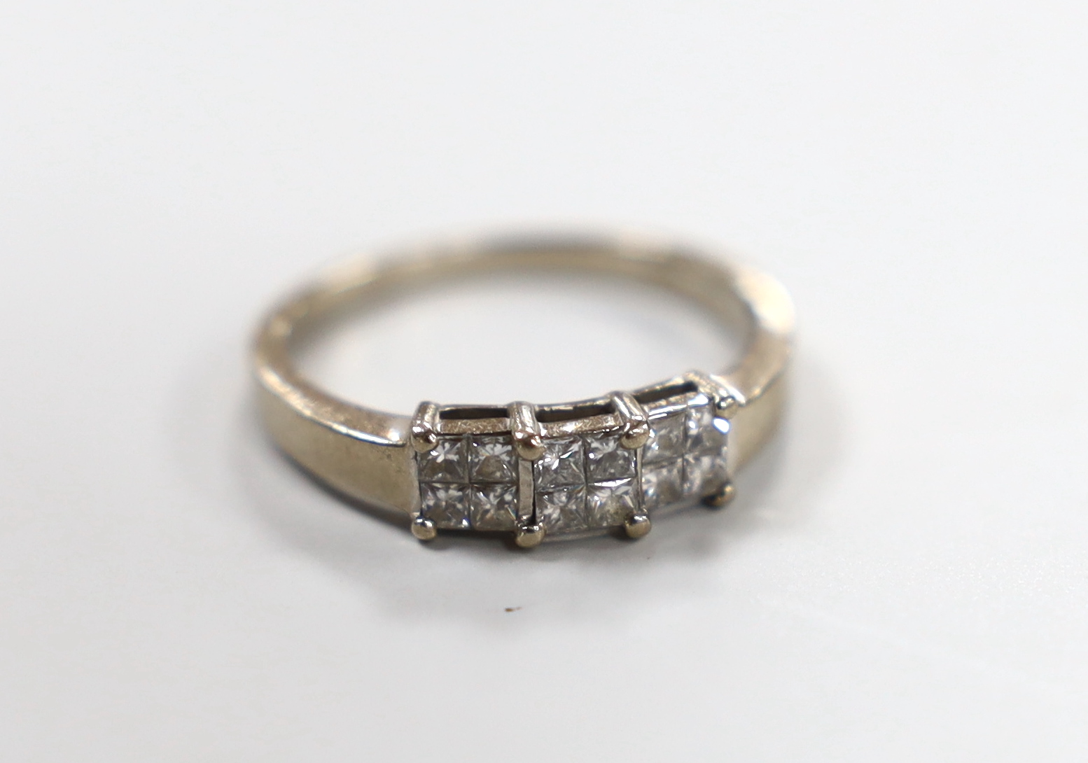 A modern 18ct white gold and twelve stone princess? cut diamond set triple cluster ring, size O, gross weight 3.2 grams.